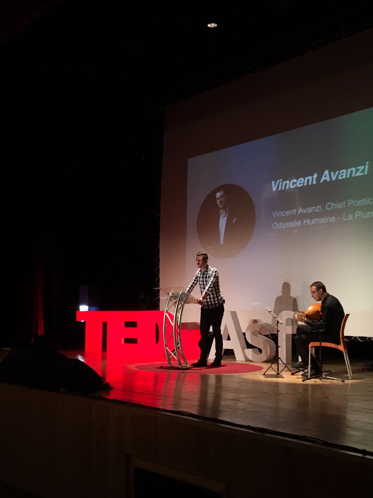 Vincent Avanzi prononce un discours poétique accompagné d’un musicien sur la scène TEDx
